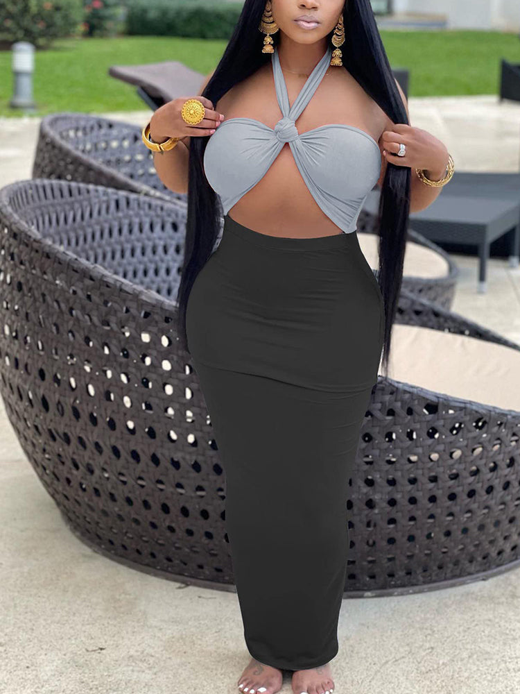 Woman wearing a light grey halter crop top with a knot detail and a black maxi skirt.
