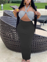 Woman wearing a light grey halter crop top with a knot detail and a black maxi skirt.