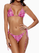 Woman wearing a pink leopard print halter bikini top and tie-side bikini bottoms, front view.