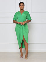 Woman wearing a green V-neck, short-sleeve, ruched, draped midi dress with a tulip hem.