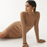 Woman wearing a brown ribbed knit turtleneck mini dress with long sleeves and cinched side detail, lying on the floor and looking to the side.