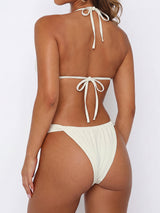 Back view of a woman wearing a light-colored bikini.