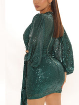 Rear view of a model in a green sequin wrap dress with puff sleeves and a fitted silhouette.