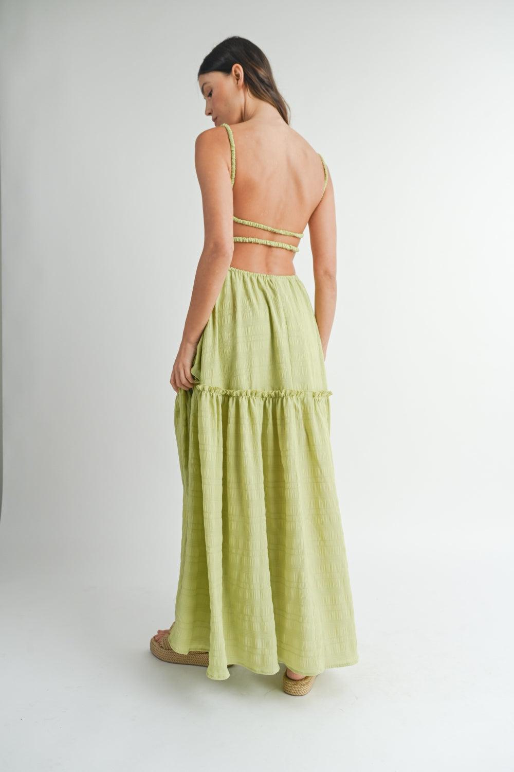 back view of a woman in a lime green maxi dress with a low back and tiered skirt