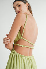 close-up of the back of a woman's shoulders and upper back, showing the cutout details and straps of a lime green dress