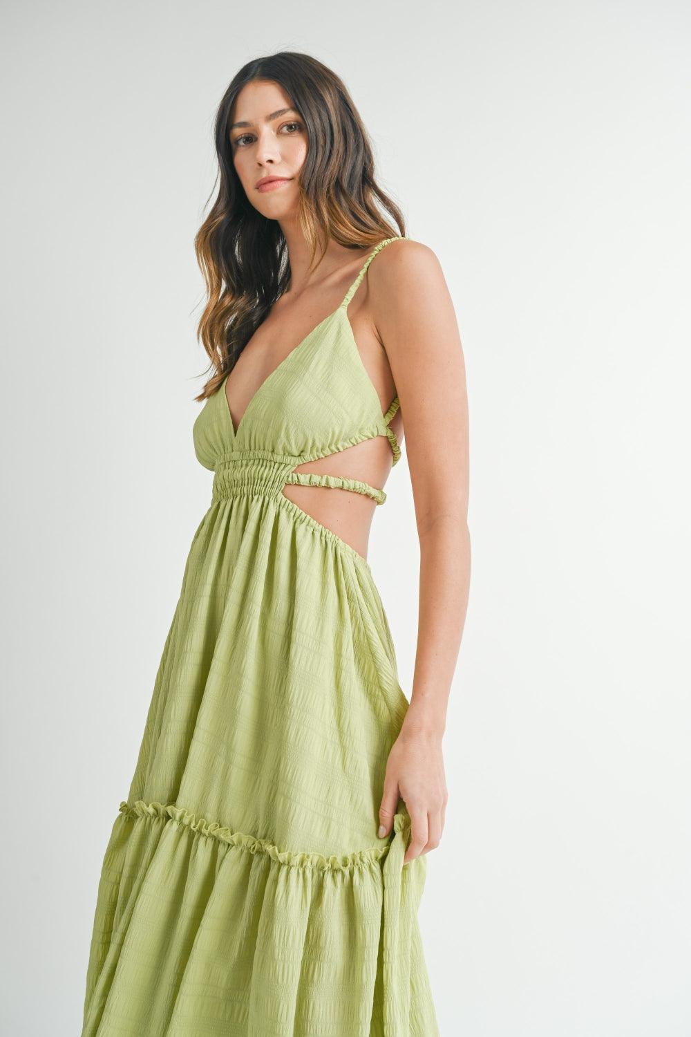 woman in a lime green maxi dress with a plunging neckline and side cutouts, posing with her hand in the skirt