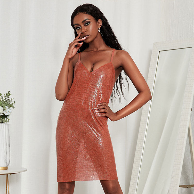 Woman wearing a sparkling rust-colored sequined mesh midi dress with spaghetti straps and a v-neck.