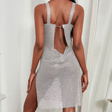 Back view of a woman in a silver sparkling mini dress with an open back featuring a chain detail and a high slit.