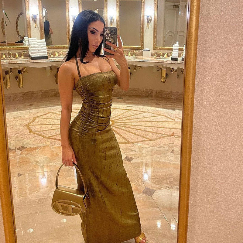Woman taking a mirror selfie in a shimmering gold maxi dress, holding a handbag.