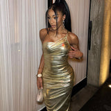 Close-up of a woman in a gold metallic one-shoulder ruched maxi dress, showing fabric detail.