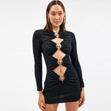 Model wearing a black long-sleeve mini dress with cut-outs and gold hardware