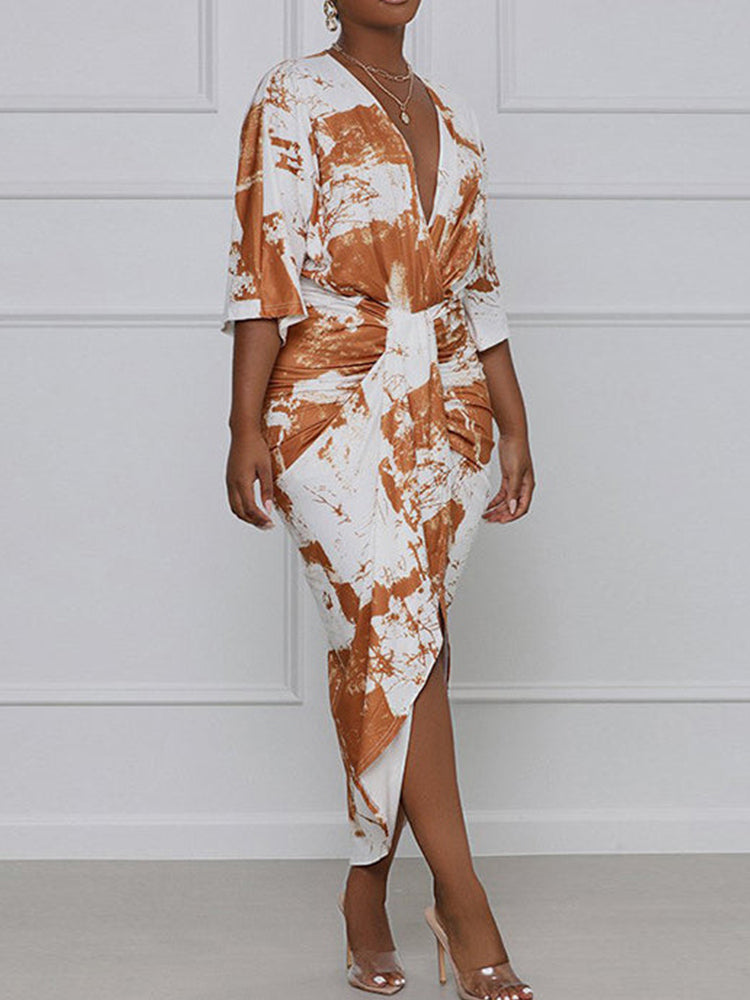 Woman wearing a brown and white tie-dye print wrap dress with a v-neck and high slit.