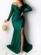 Woman wearing a green off-the-shoulder long-sleeved mermaid gown with a high slit