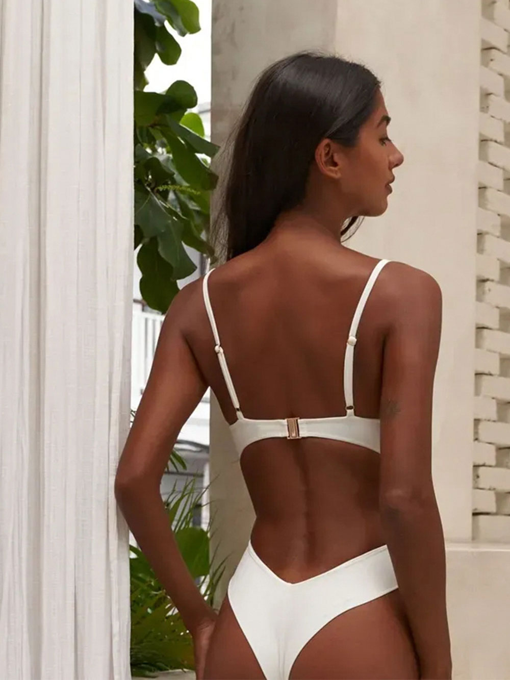 Back view of a woman wearing a cream one-piece swimsuit