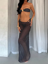 Woman wearing a black and white polka dot bandeau bikini top and a matching sheer polka dot maxi skirt.