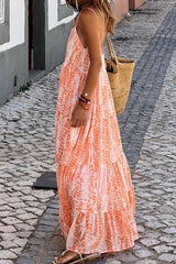 Side view of a woman in an orange and white tie-dye maxi dress walking on a cobblestone street.