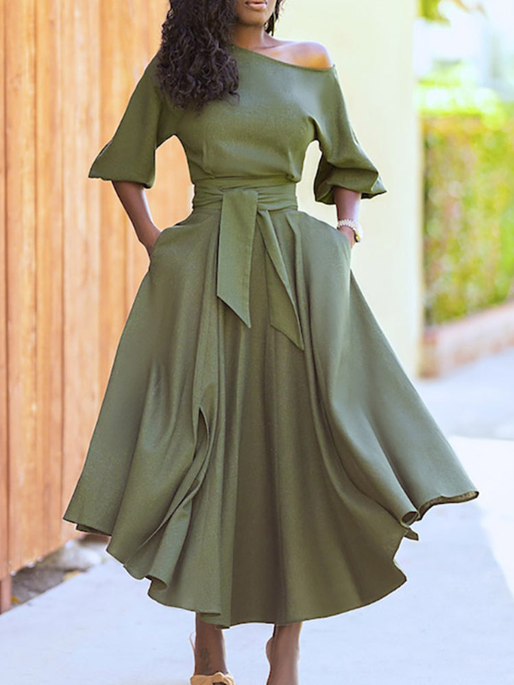 Woman wearing a green off-the-shoulder midi dress with a belted waist and full skirt