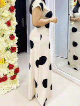 Full length shot of a woman wearing a cream and black polka dot maxi dress.