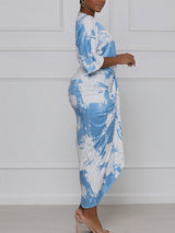 Side view of a woman in a blue and white tie-dye print wrap dress.