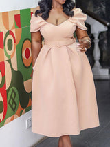 Woman in a light pink off-the-shoulder dress with a belted waist and pleated skirt, showing the detail of the neckline and sleeves.