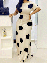 Side view of a woman in a cream and black polka dot maxi dress with short sleeves.