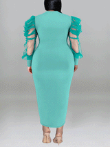 Back view of a woman in a teal sheath dress with sheer puff sleeves