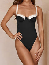 Woman in a black and white one-piece swimsuit, front view.