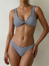 Woman wearing a blue and white striped bikini with a knotted front top and high-waisted bottoms