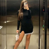 woman in black dress with beaded trim and side slit posing in an elevator