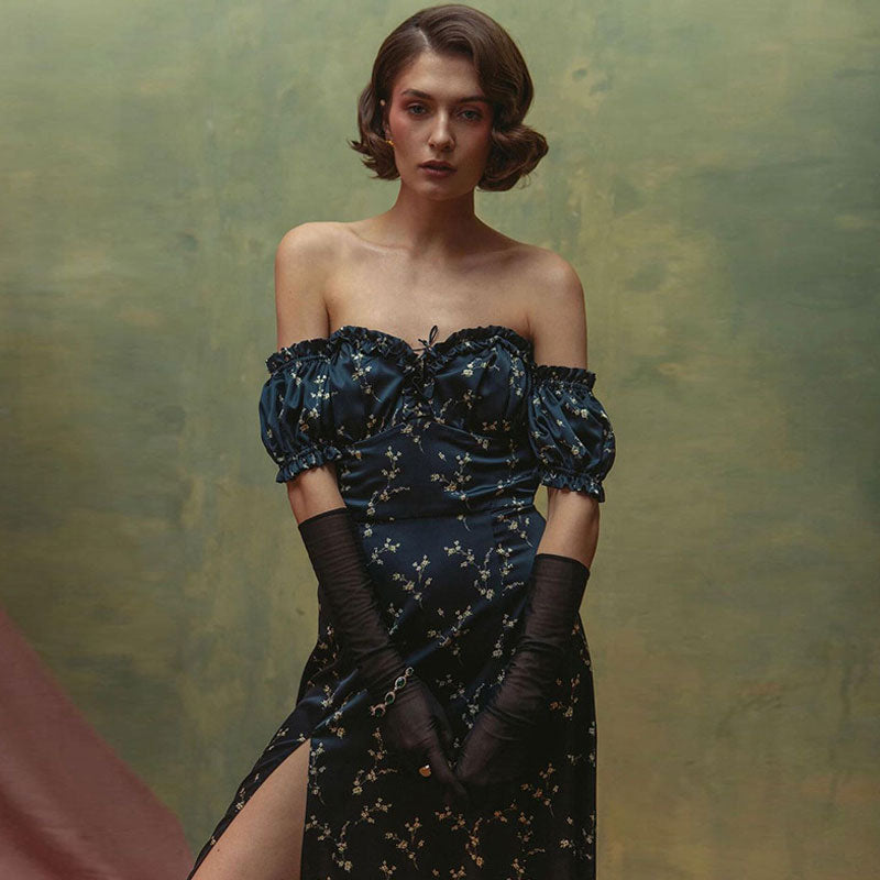 Close-up of a woman wearing a dark blue floral print off-the-shoulder dress with puff sleeves and long sheer gloves.