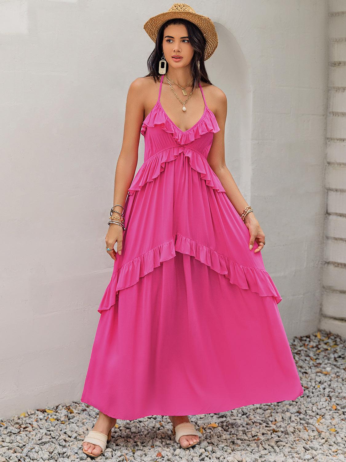 Woman wearing a pink tiered maxi dress with ruffle trim and a v-neckline, accessorized with a straw hat.