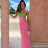 Woman wearing a pink and green maxi dress with cut-outs and a high slit