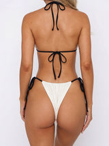 Back view of a woman wearing a cream-colored bikini with black ties, showing the adjustable straps and tie closures.