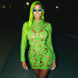 Woman wearing a green long-sleeved mini dress with cut-out details and green sunglasses