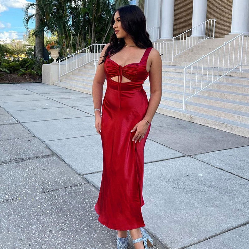 woman in a red satin slip dress with a cutout and thigh-high slit, posing outdoors