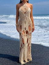 Woman wearing a beige crocheted maxi dress with cut-out details on a beach.