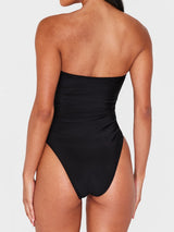 Back view of a woman wearing a black strapless one-piece swimsuit