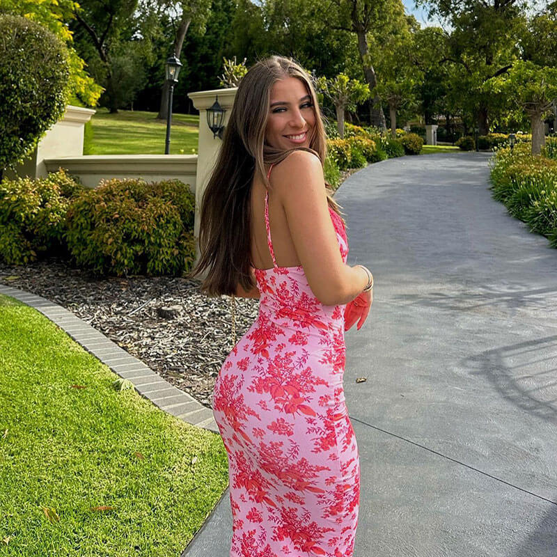 Woman wearing a pink floral print slip dress walking outdoors and looking over her shoulder