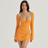 Woman wearing an orange long-sleeve mini dress with a halter neckline and ruched detailing.