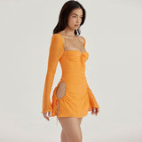 Side view of a woman in an orange sheer chiffon mini dress with cutouts and drawstring details.