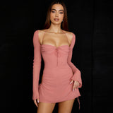 Model wearing a pink ruched mini dress with cut-out sides and long bell sleeves, front view.
