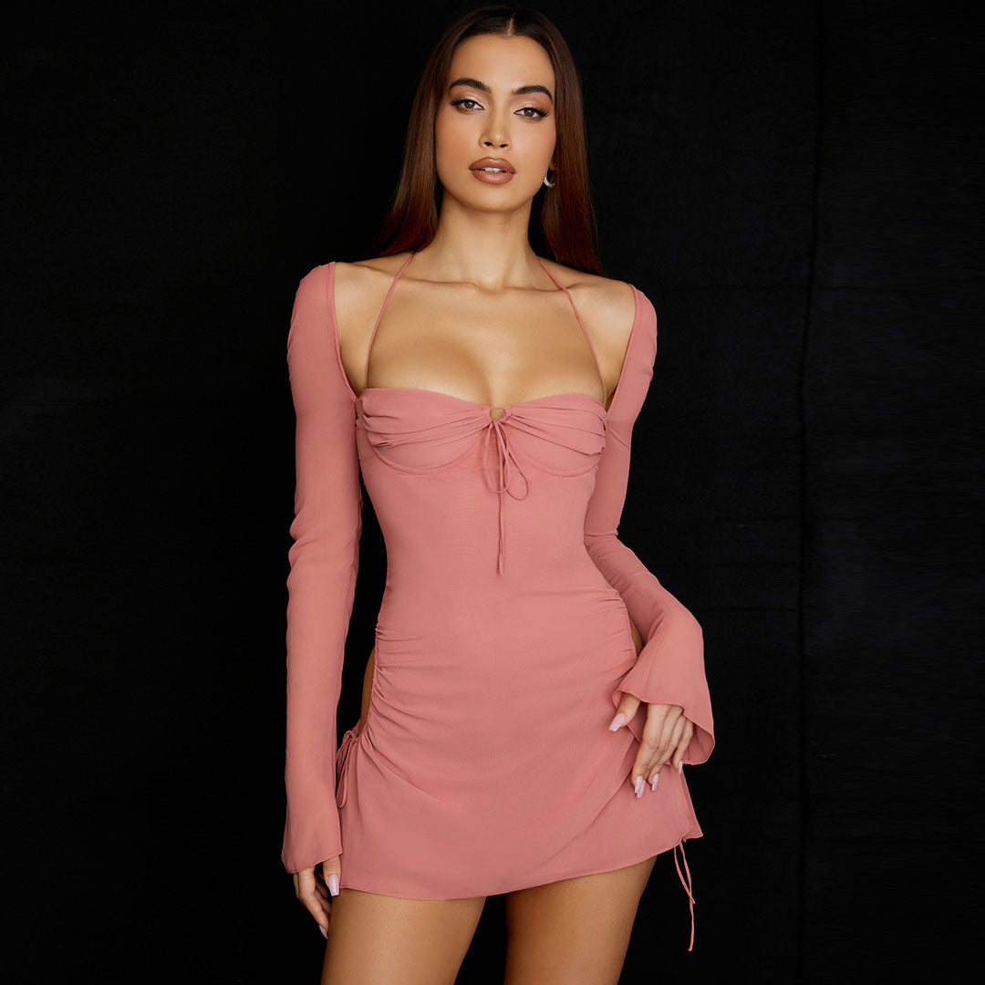 Model wearing a pink ruched mini dress with cut-out sides and long bell sleeves, front view.