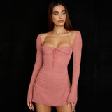Model wearing a pink ruched mini dress with cut-out sides and long bell sleeves, angled side view.