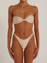 Front view of a woman wearing a beige shimmering strapless bikini set with a twisted knot top and high-cut bottoms.