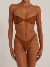 Front view of a woman wearing a brown shimmering strapless bikini set with a twisted knot top and high-cut bottoms.