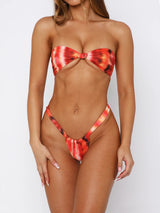 Woman wearing a red and orange tie-dye strapless bikini with a knotted front