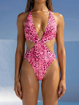 Woman wearing a pink leopard print one-piece swimsuit with a plunging neckline and cut-out details
