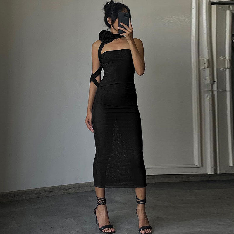 Woman wearing a black strapless mesh dress with a large black flower detail on the shoulder and thin straps.