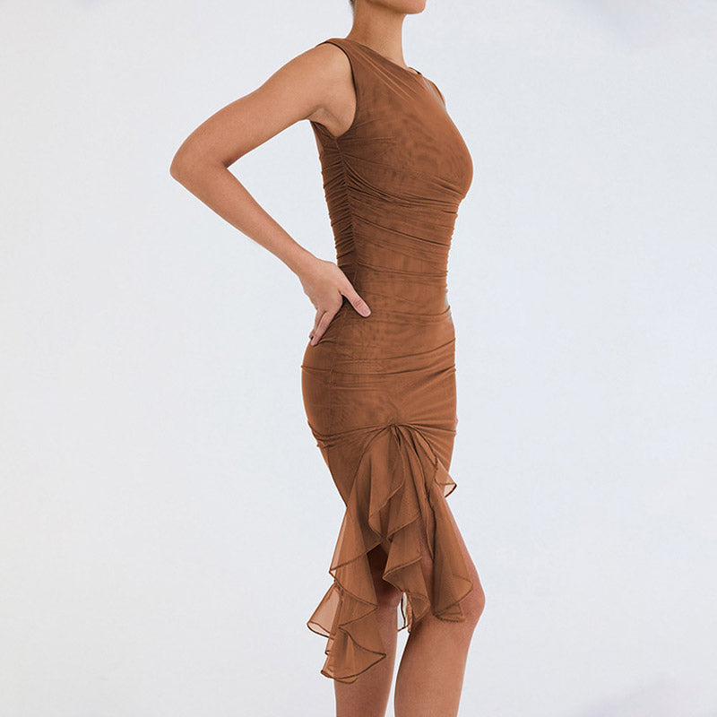 Woman wearing a brown sheer mesh ruched dress with a ruffled asymmetrical hemline, posing from the side.