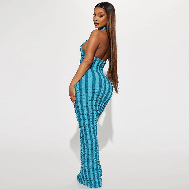 Back view of a woman wearing a turquoise and blue striped crinkle knit halter maxi dress